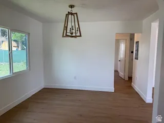 Unfurnished dining area with dark wood-type flooring and hanging lights