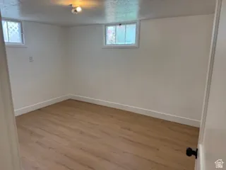 Basement with wood finished floors and a textured ceiling