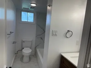 Full bath with vanity, light marble finish floors, and a combined bath / shower with marble appearance