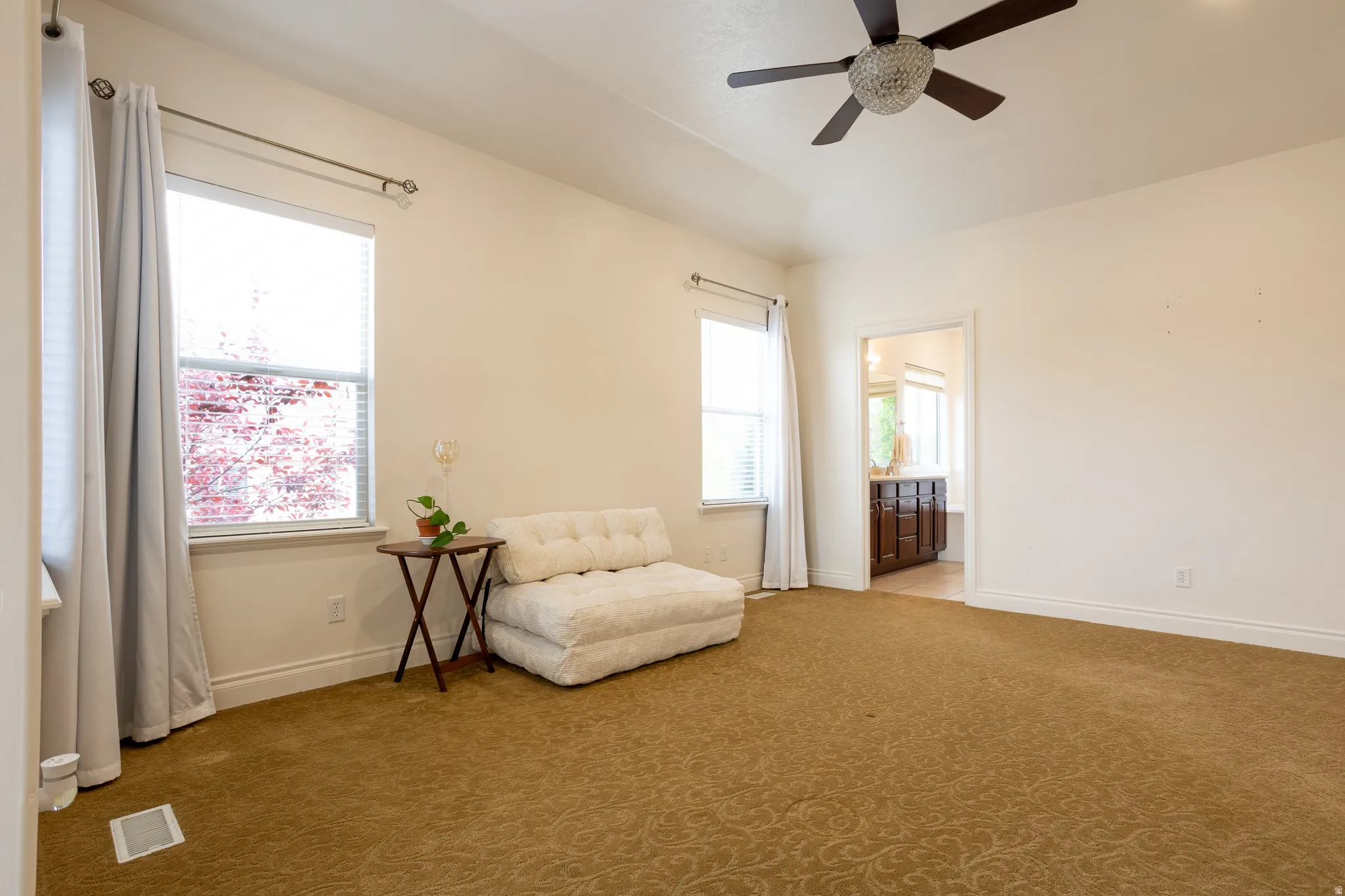 Living area featuring light colored carpet, healthy amount of natural light, and a ceiling fan