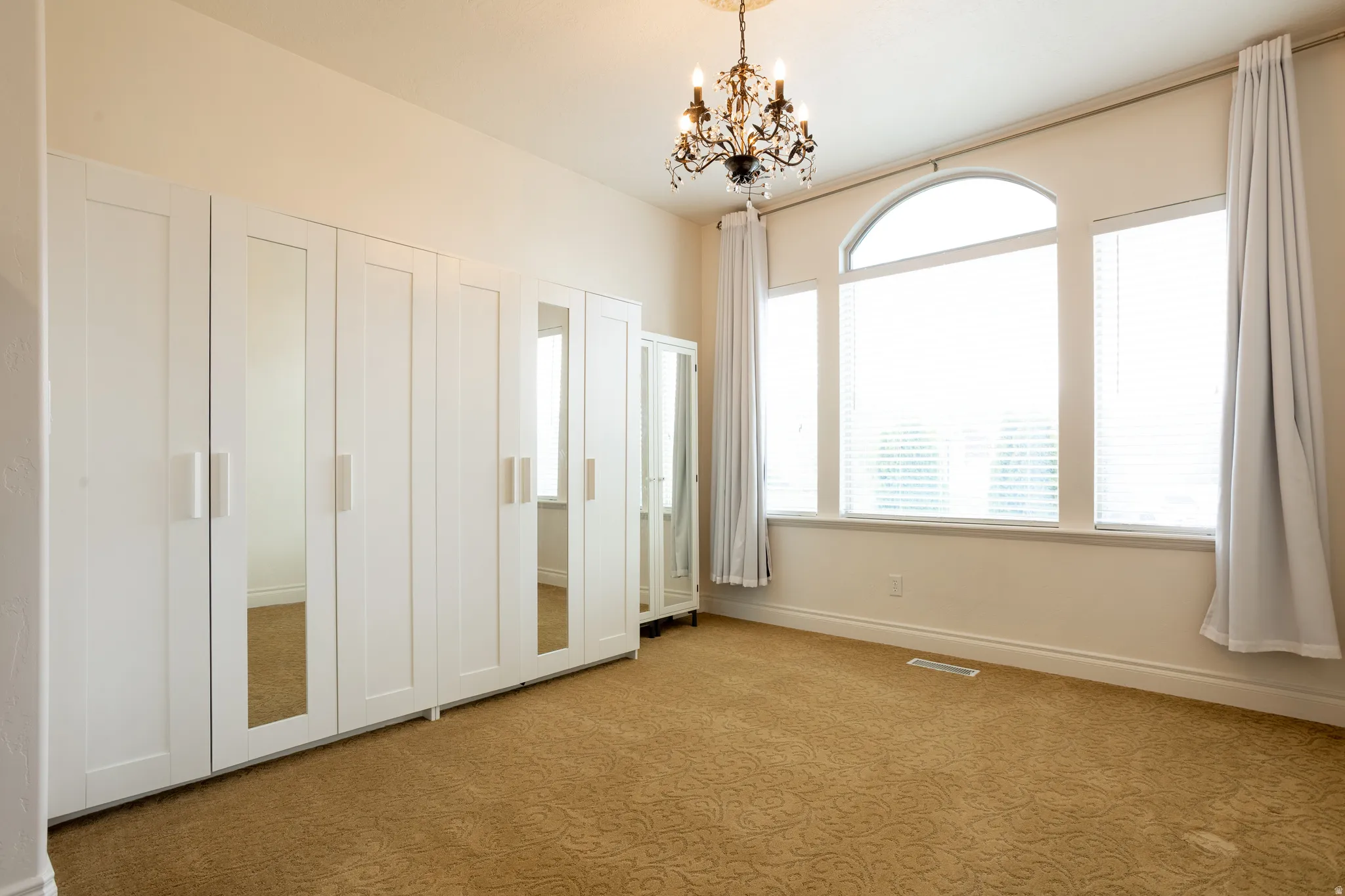 Unfurnished bedroom with carpet flooring and suspended lighting