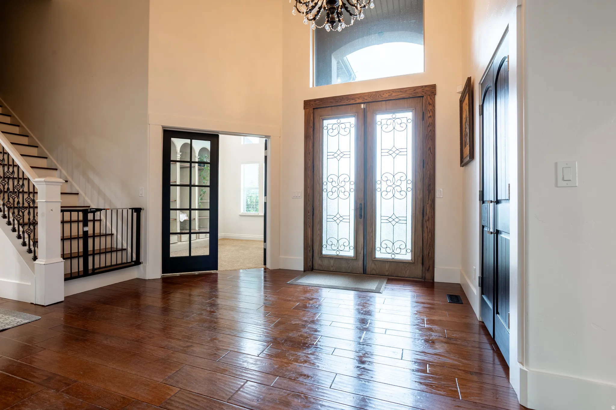 Foyer featuring french doors, hanging lights, dark wood-type flooring, and a high ceiling