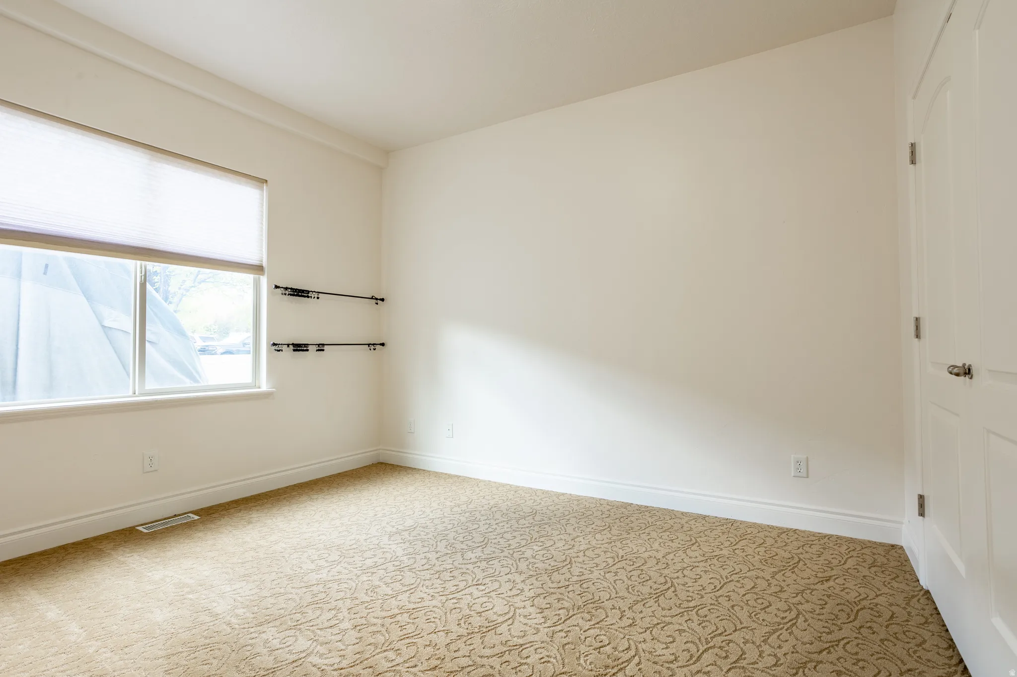 Empty room with light colored carpet and baseboards