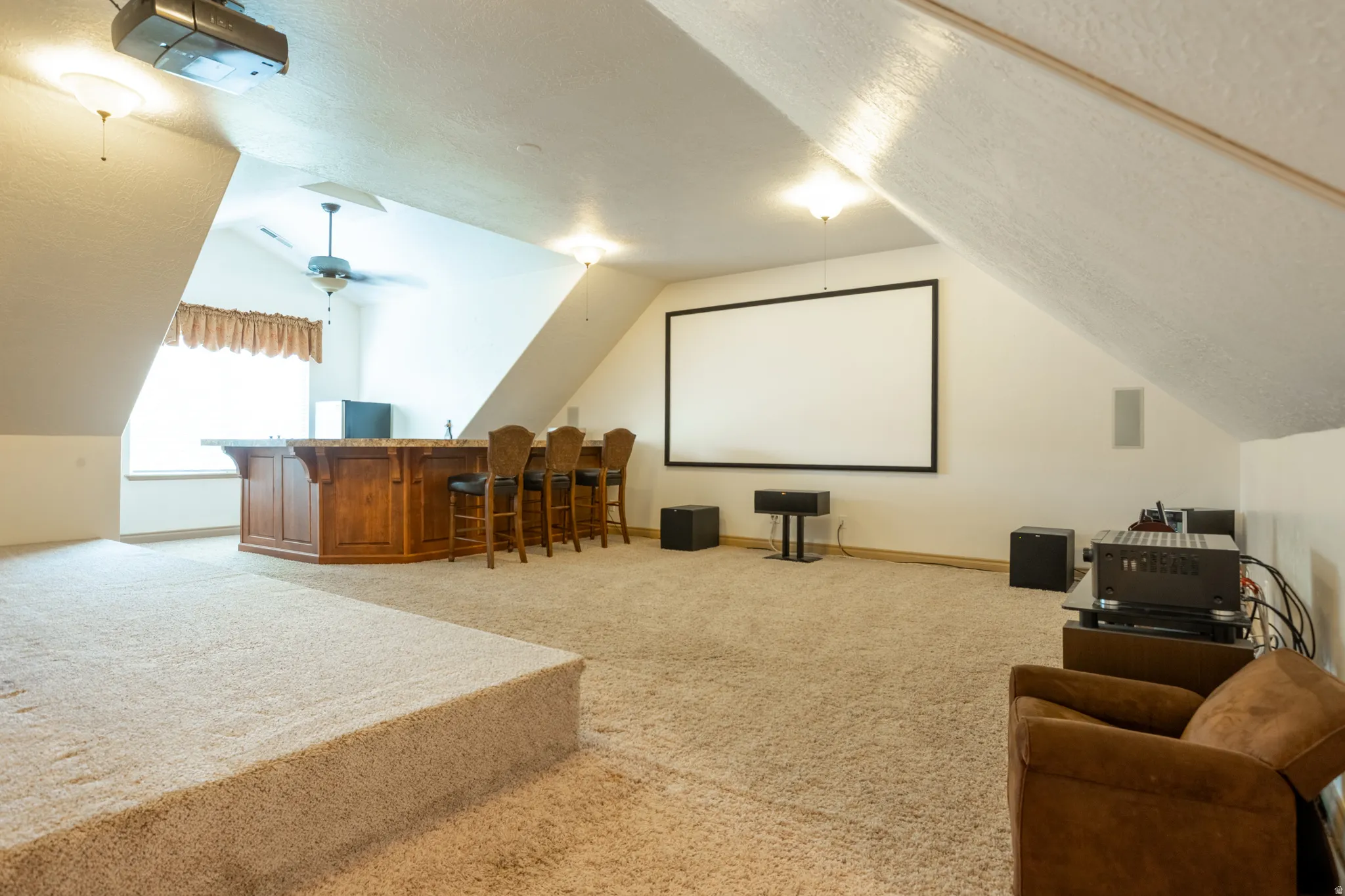 Home theater room with light carpet, a textured ceiling, and bar area