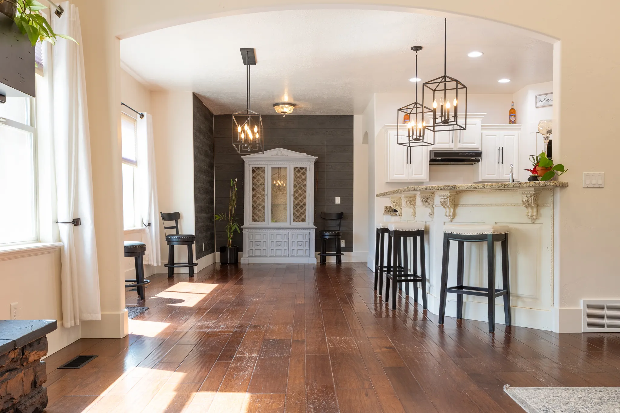 Kitchen with white cabinets, a kitchen breakfast bar, dark wood-type flooring, arched walkways, and a peninsula