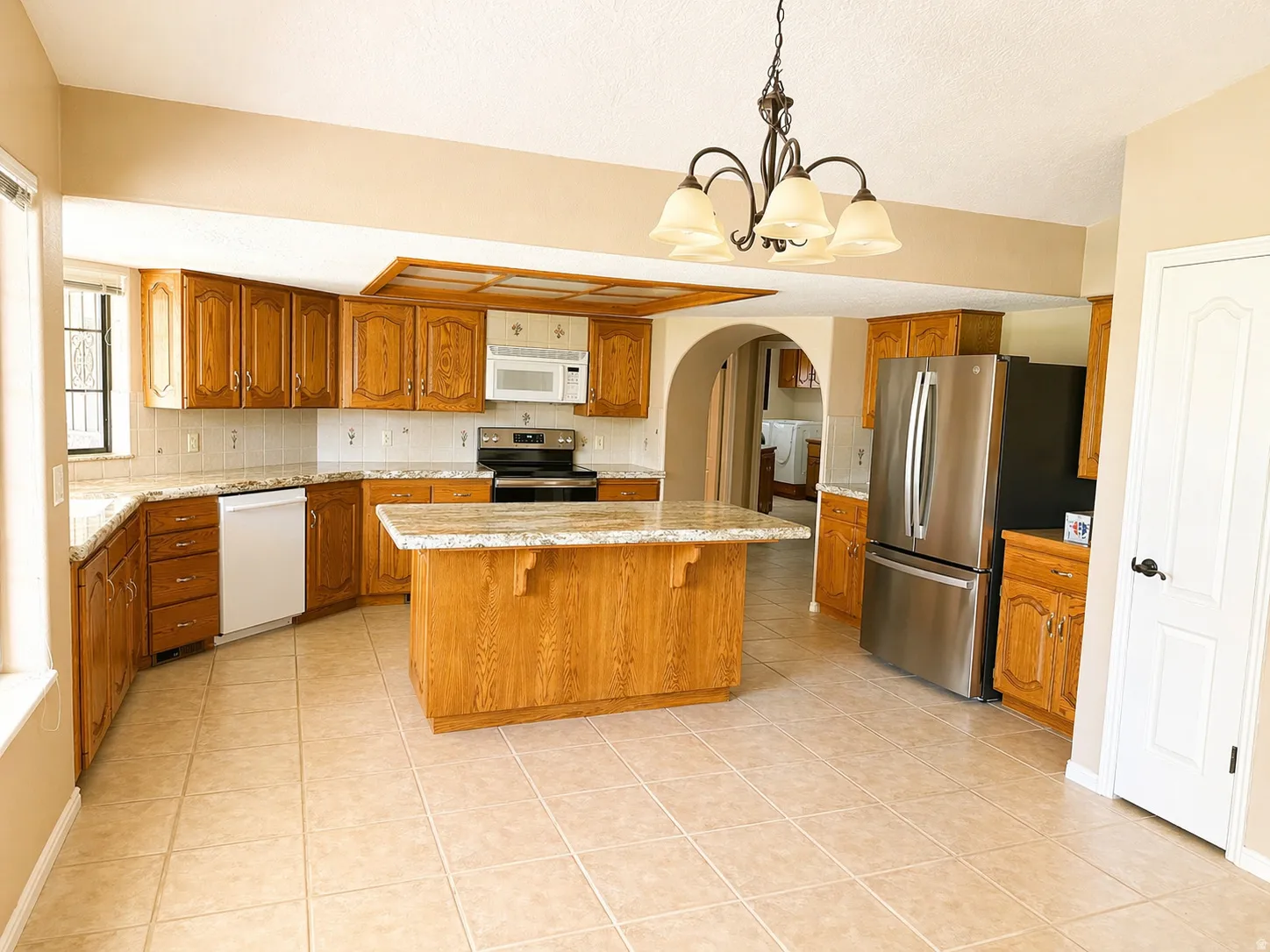 Kitchen featuring wood finish cabinetry, stainless steel appliances, a chandelier, a breakfast bar, and arched walkways