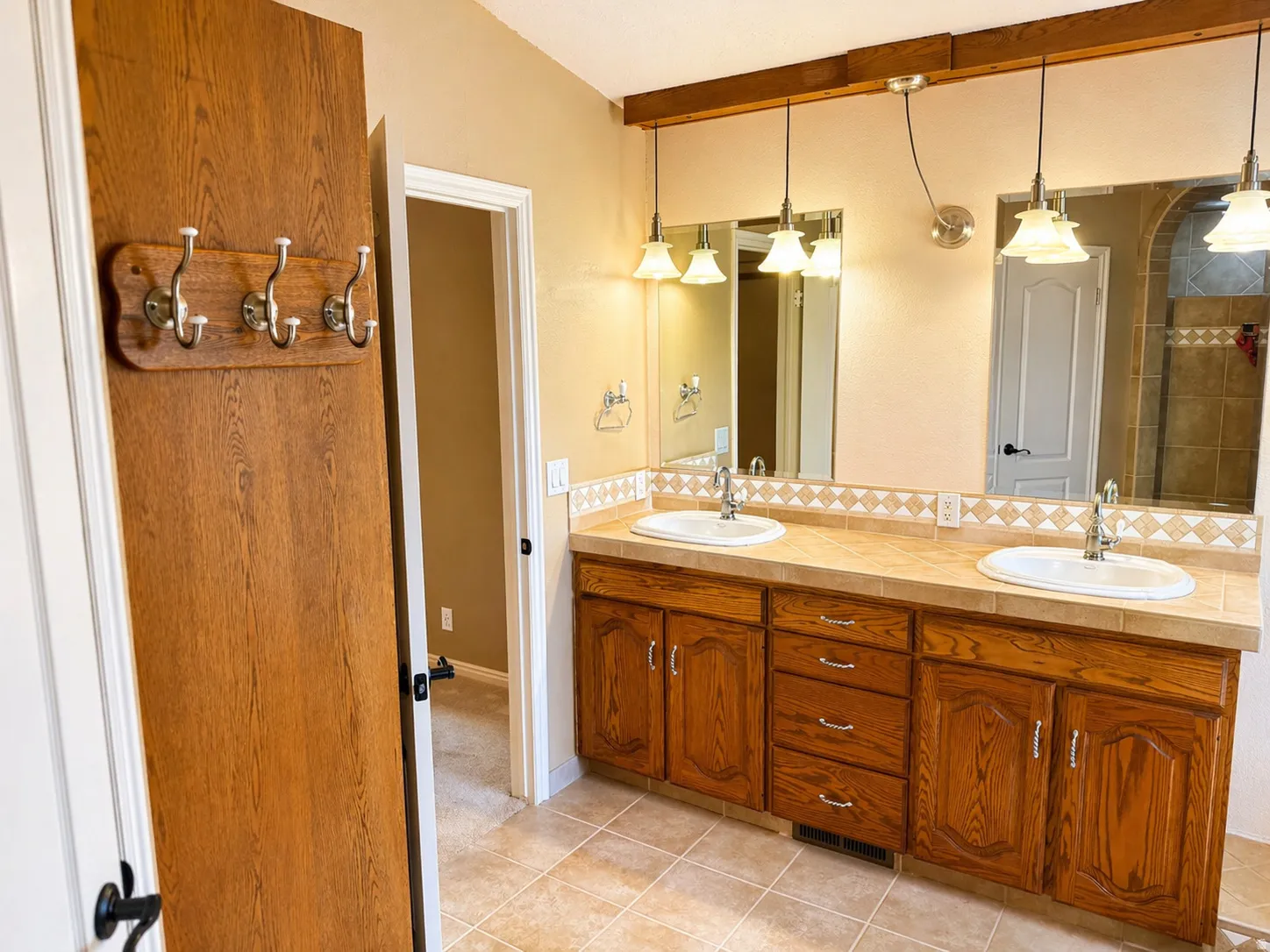 Bathroom featuring tasteful backsplash, double vanity, and light tile patterned floors