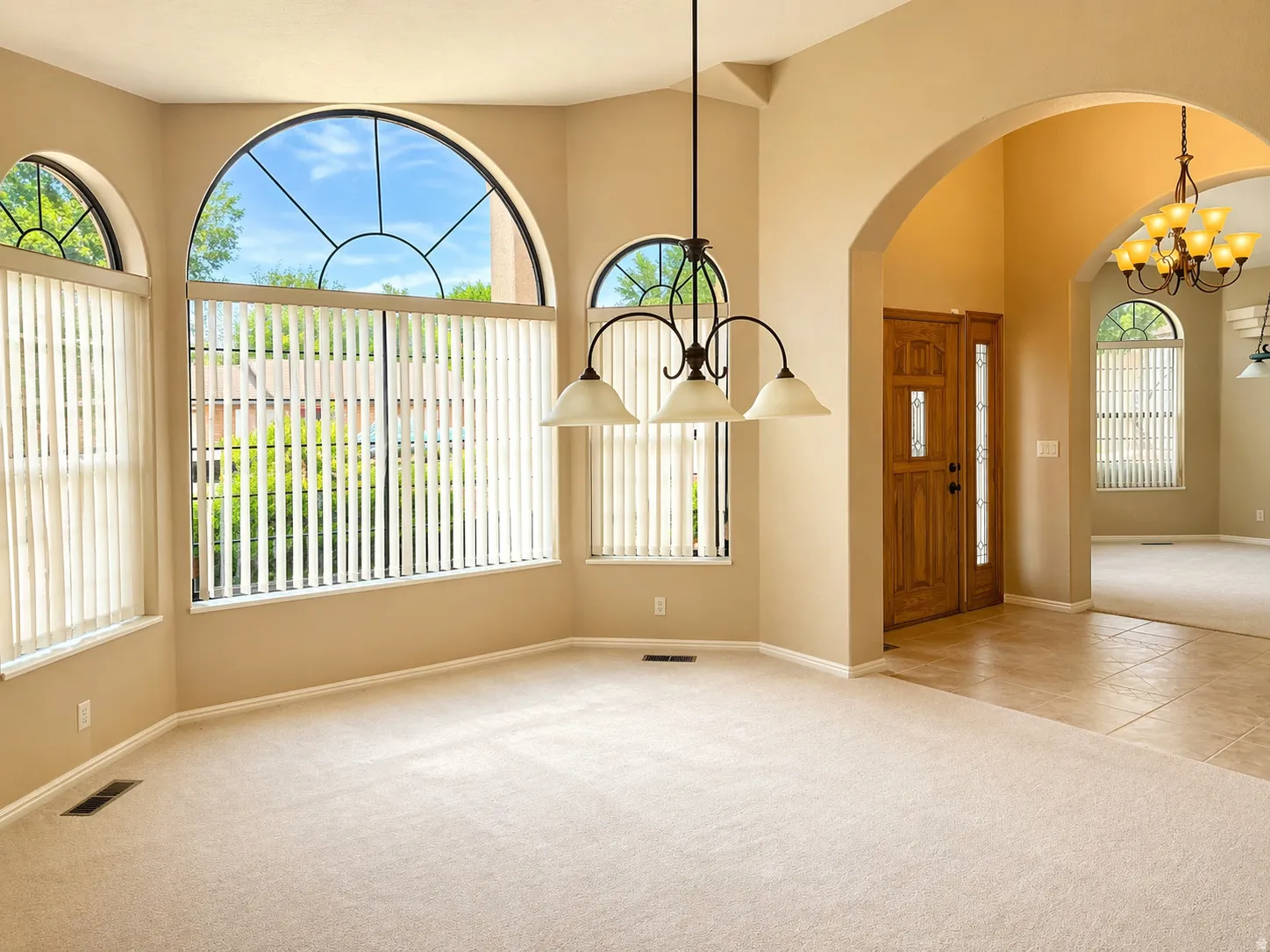 Foyer entrance featuring light colored carpet, hanging lights, arched walkways, and light tile patterned floors
