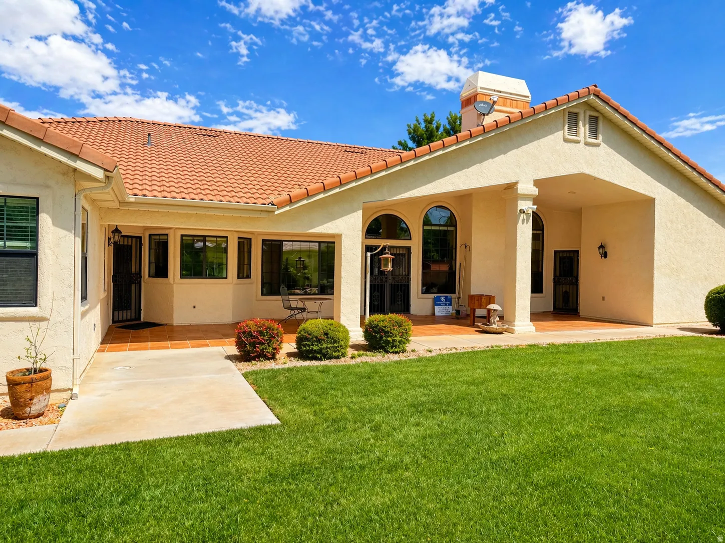 Back of house featuring stucco siding, a lawn, and a tiled roof
