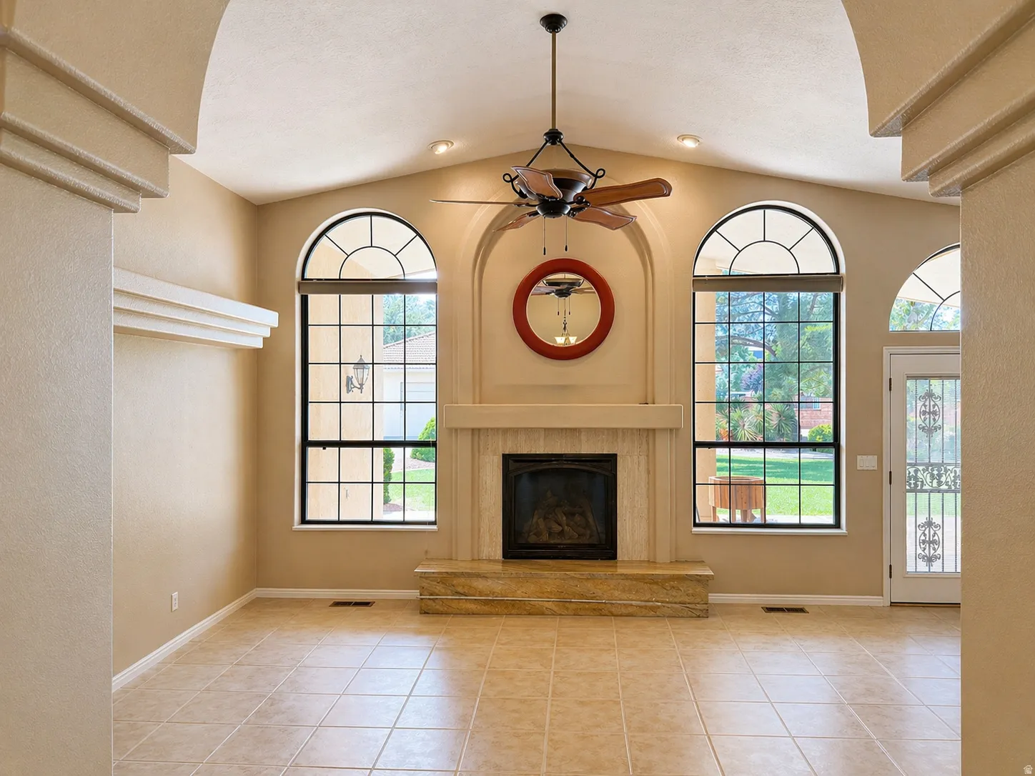 Unfurnished living room featuring a high end fireplace, a ceiling fan, light tile patterned floors, and lofted ceiling