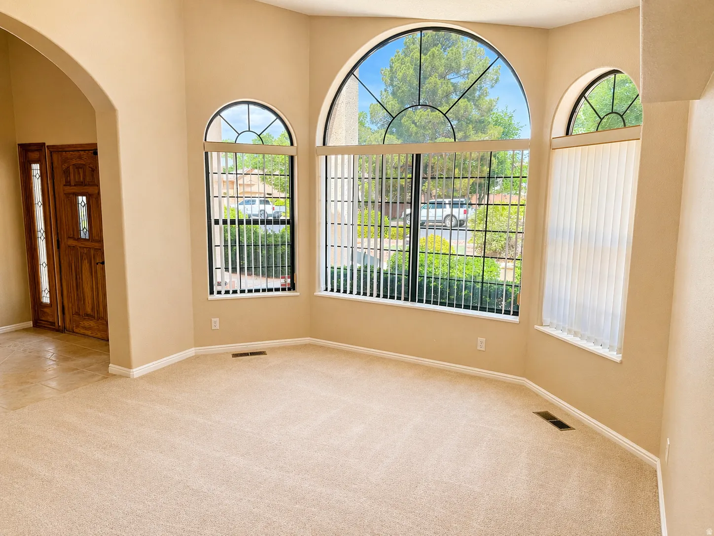 Empty room featuring light colored carpet and arched walkways