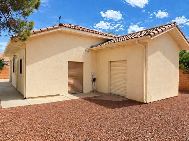 Back of house with stucco siding and a tiled roof