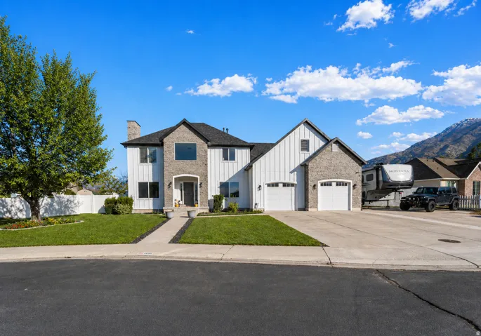 View of front of home featuring board and batten siding, concrete driveway, a chimney, a mountain view, and a garage