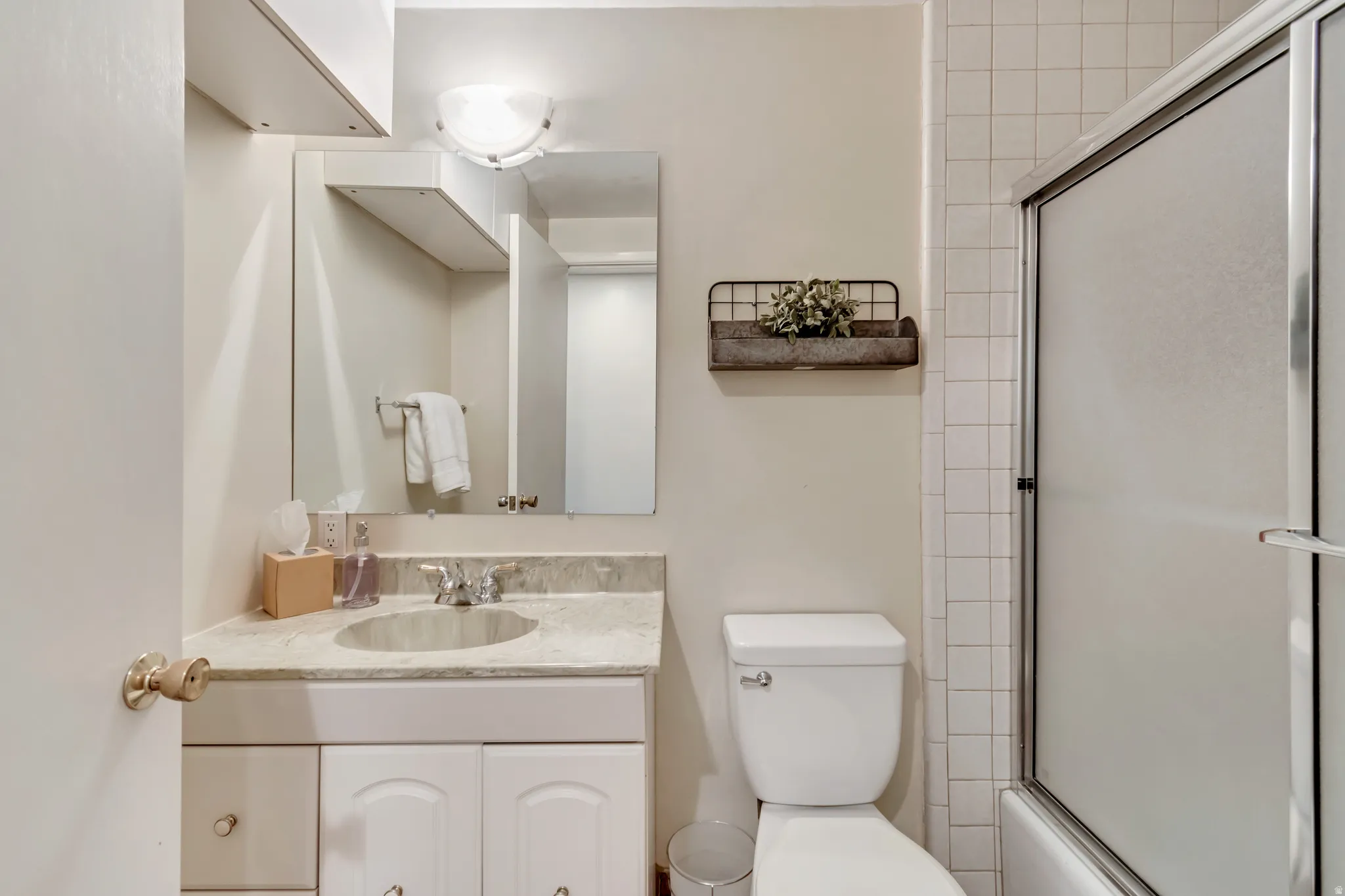 Full bathroom guest with vanity and shower/bath combination with glass door.