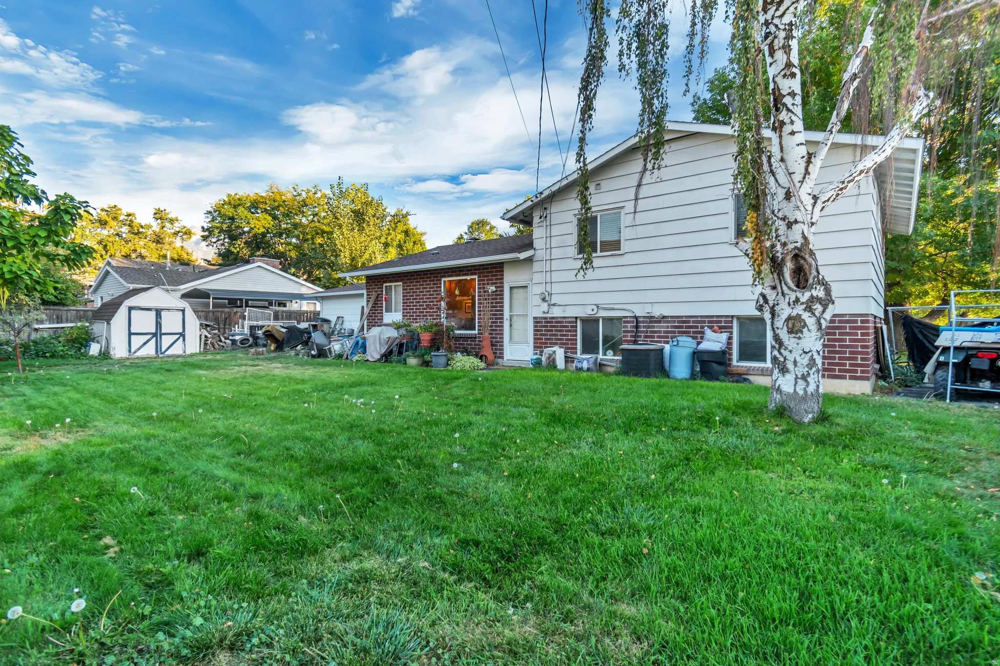 Angled view of the back of the house with a storage shed and brick siding. Ample space to entertain or start a garden.