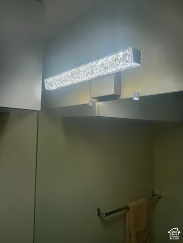 Linear LED light fixture with a textured glass shade and a polished metal base, featuring a wall-mounted mirror and a metal towel bar
