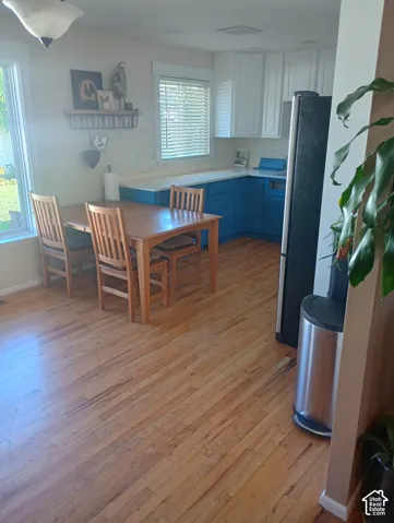 Kitchen featuring wood-finish flooring, two-tone cabinetry with white upper and blue lower units, solid-surface countertops, and recessed lighting