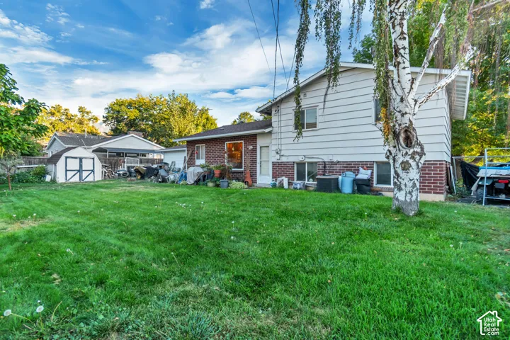 Angled view of the back of the house with a storage shed and brick siding. Ample space to entertain or start a garden.