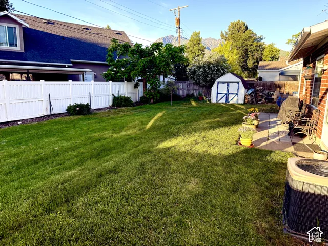 Expansive backyard featuring a large green lawn, a white vinyl privacy fence, and a patio area