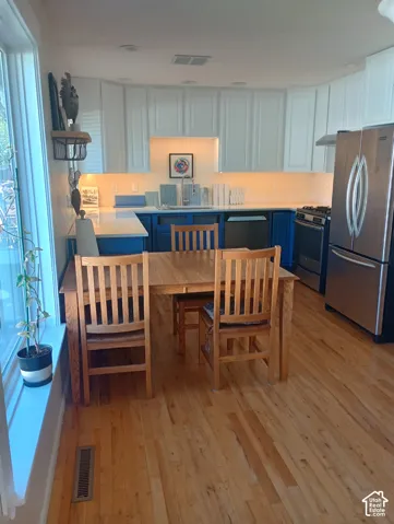 Kitchen featuring dual-tone cabinetry, stone-surface countertops, stainless steel appliances, and wood-finish flooring