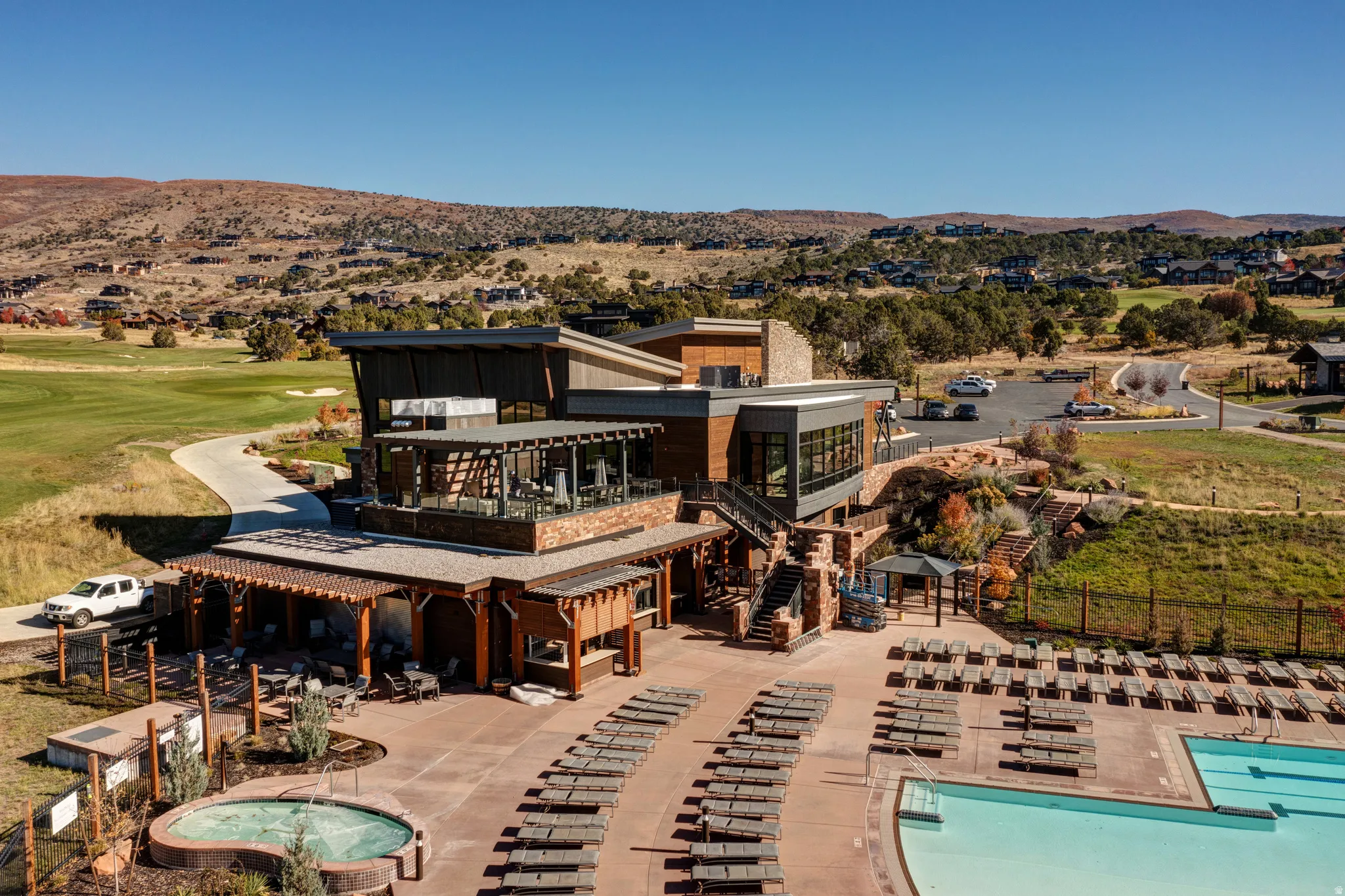 Rear view of house with a patio, a balcony, a community pool, a mountain view, and a hot tub
