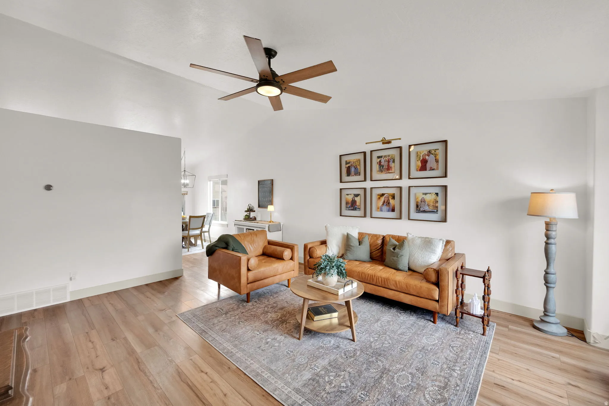 Living room featuring light wood-style flooring, ceiling fan, and vaulted ceiling