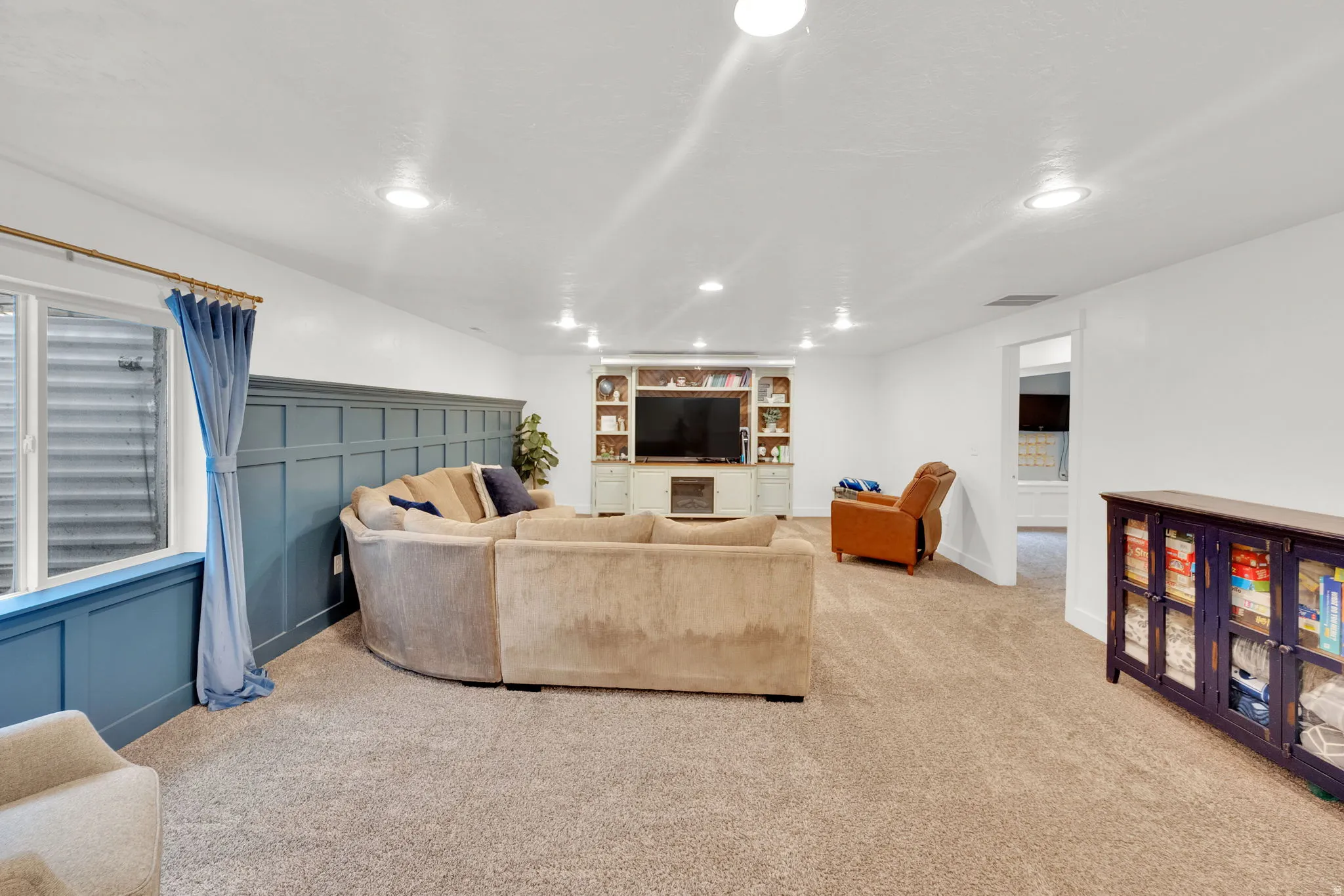 Living area featuring a decorative wall, light colored carpet, and recessed lighting