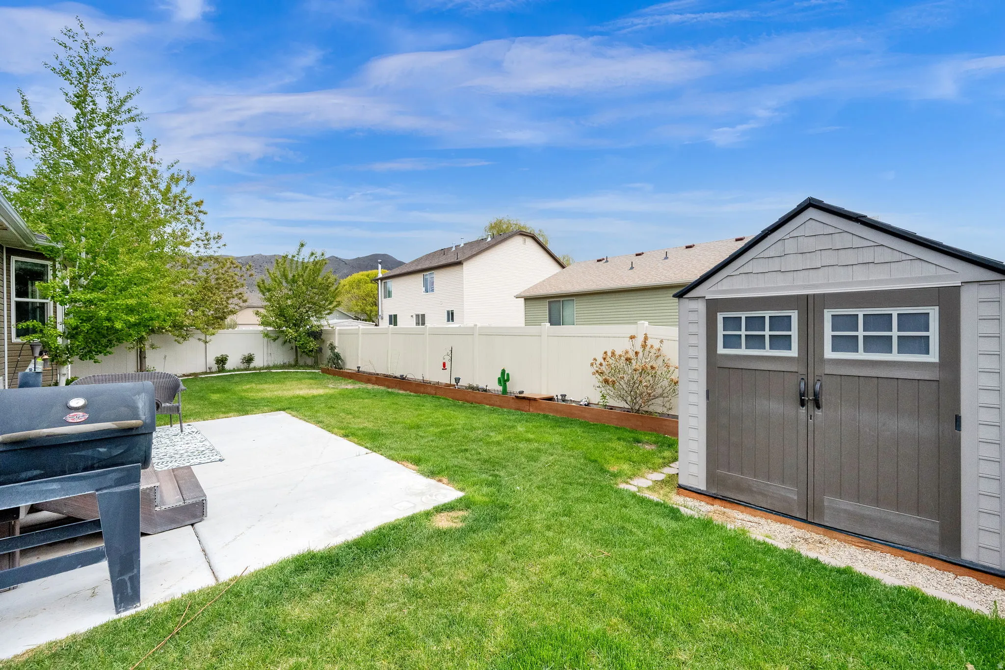 Fenced backyard with a shed, a patio, and a mountain view