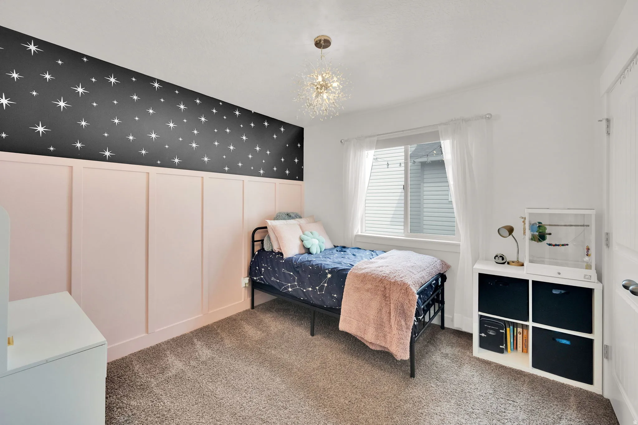 Carpeted bedroom featuring wallpapered walls, a decorative wall, a wainscoted wall, an accent wall, and hanging lights