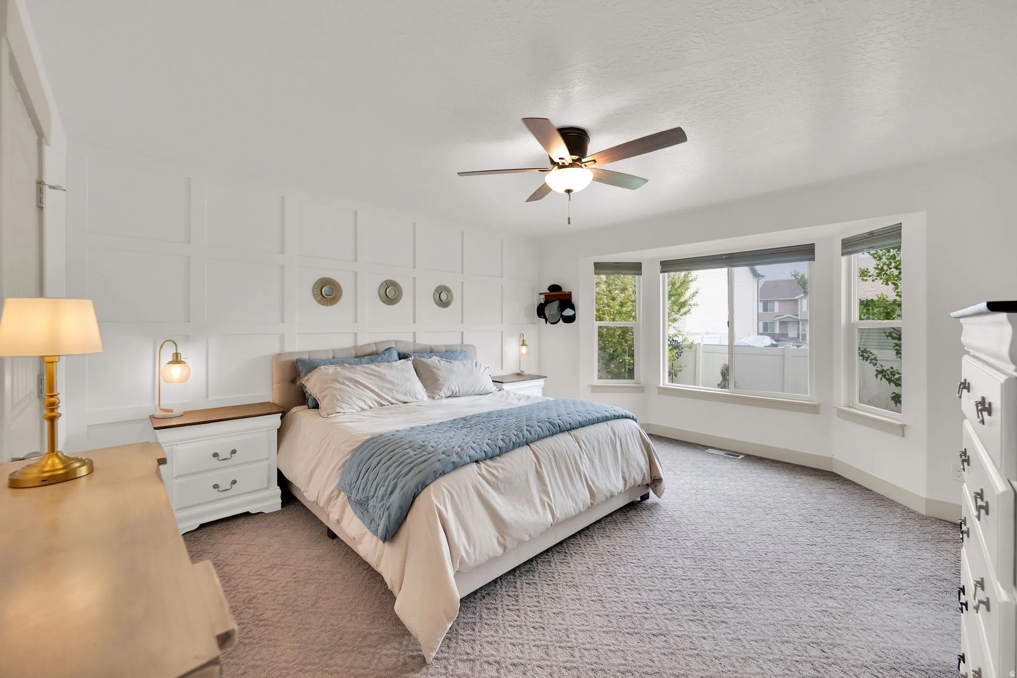 Bedroom featuring light carpet, a decorative wall, and ceiling fan