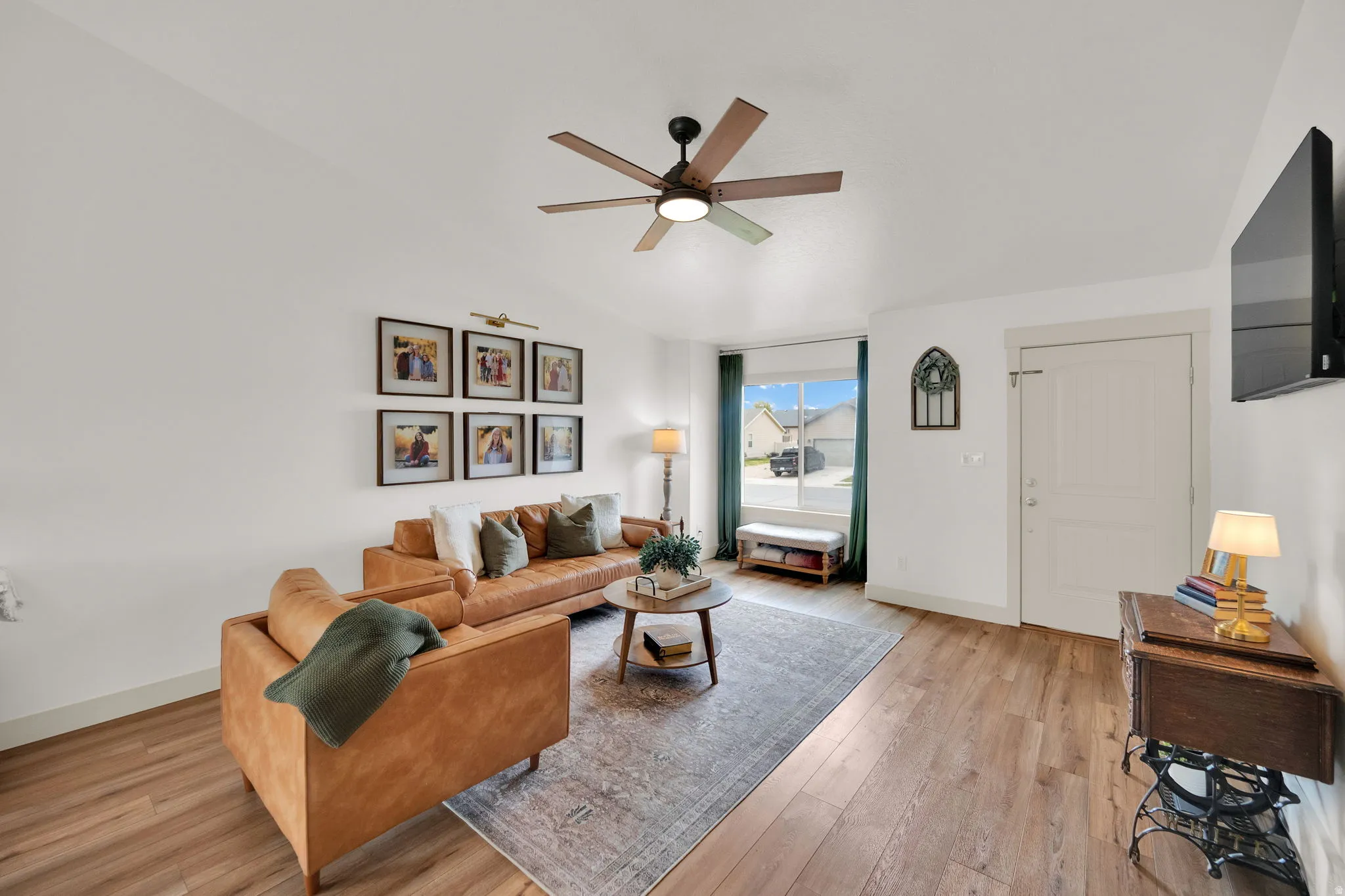 Living room featuring light wood-type flooring, ceiling fan, and lofted ceiling