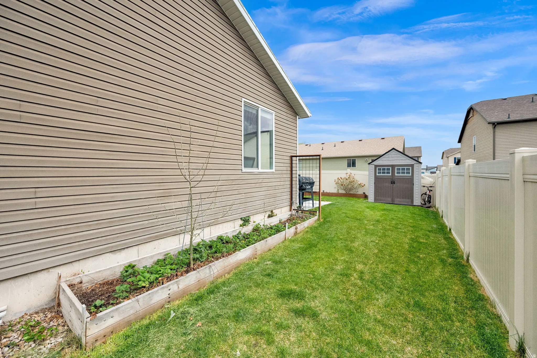 Fenced backyard with a storage shed and a garden