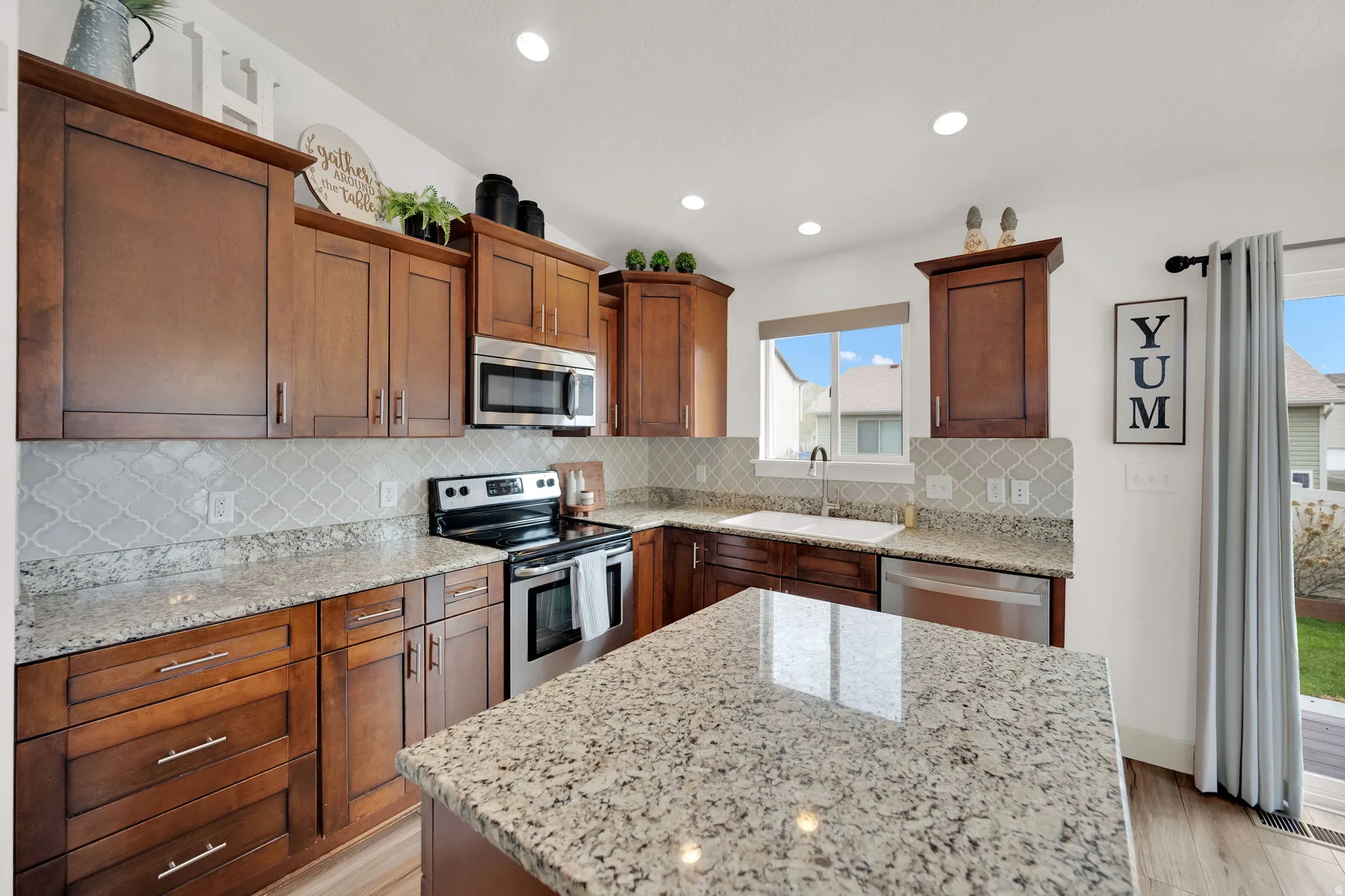 Kitchen featuring stainless steel appliances, light stone counters, a kitchen island, and recessed lighting