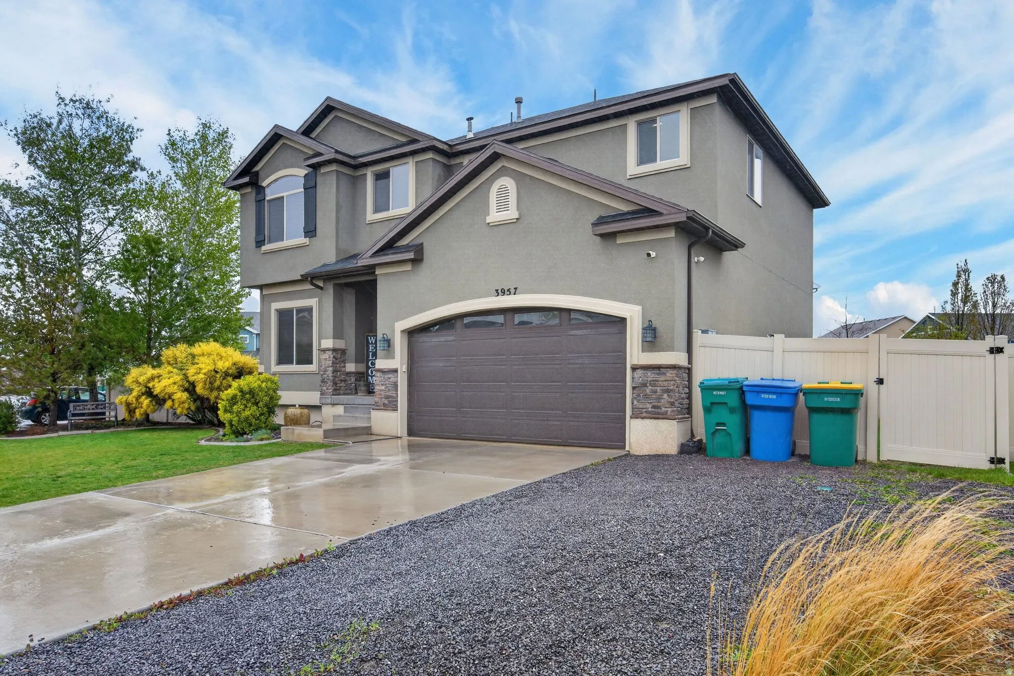 Traditional-style home featuring a gate, concrete driveway, stucco siding, and stone siding