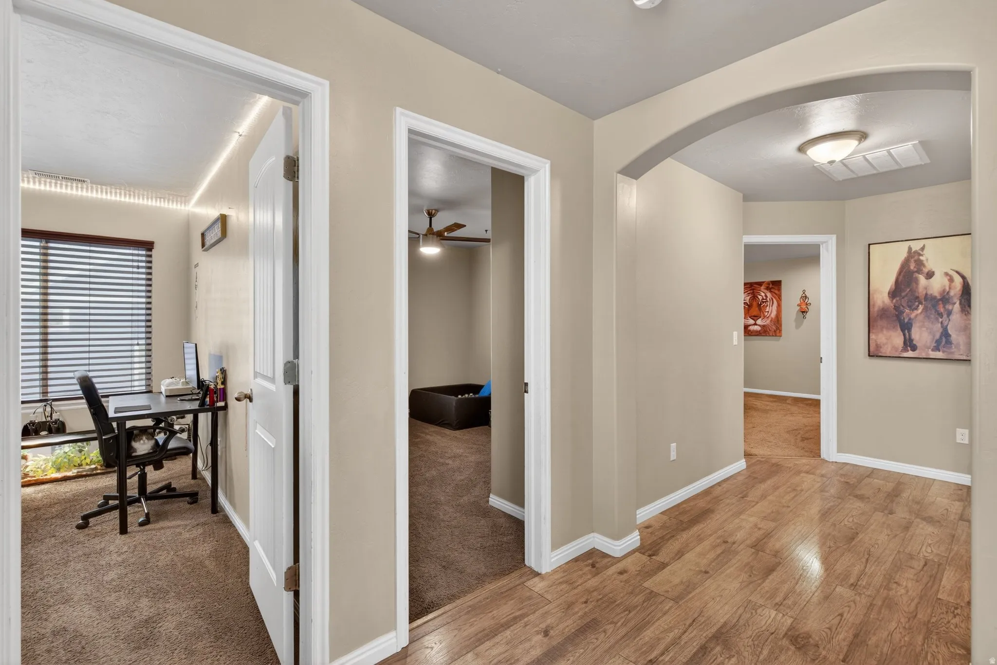 Hallway featuring light wood-type flooring, arched walkways, and a desk
