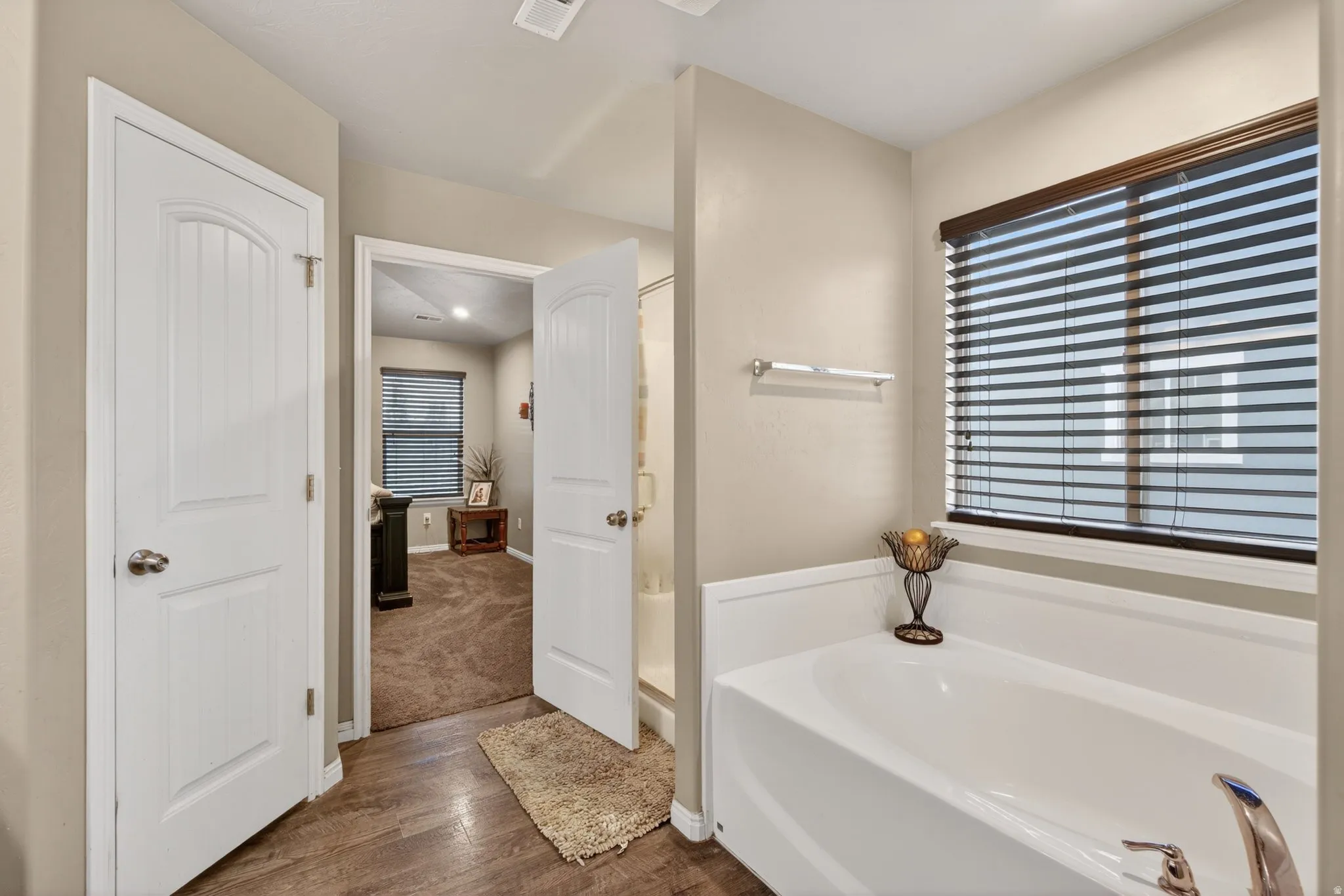 Bathroom with a bath, dark wood-style floors, and a shower stall
