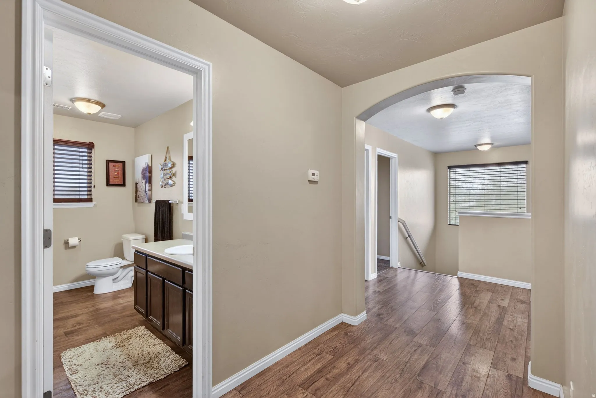 Corridor featuring dark wood-style floors, arched walkways, plenty of natural light, and an upstairs landing