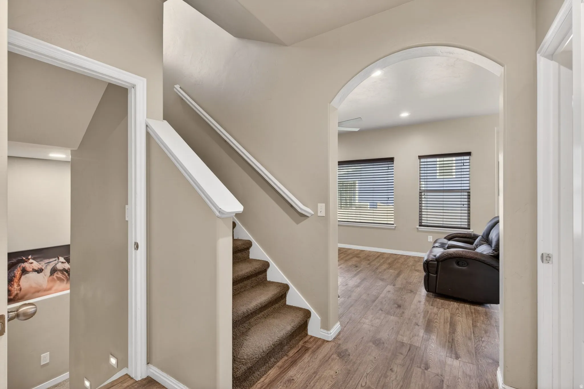 Stairway featuring arched walkways, wood finished floors, and recessed lighting