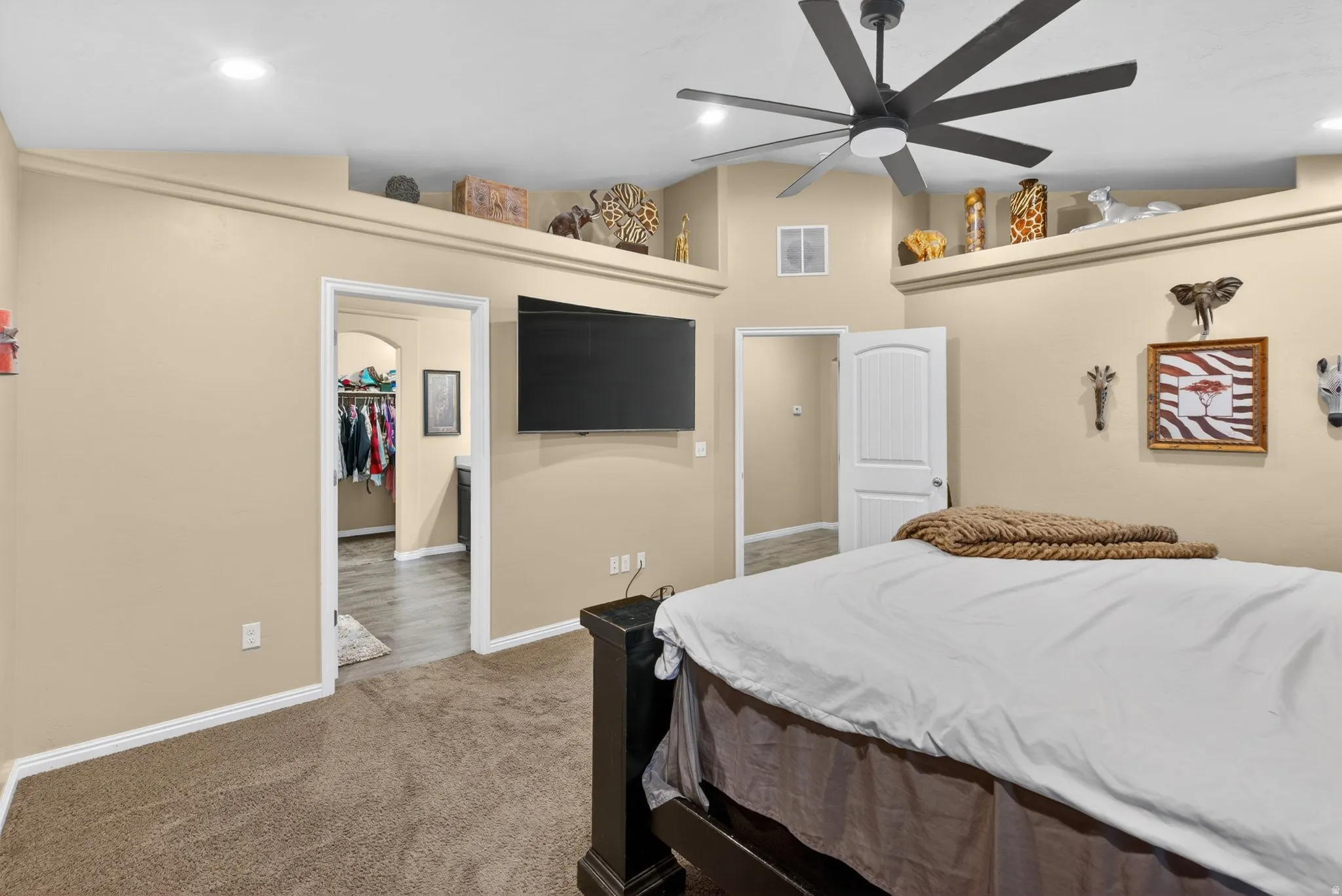 Carpeted bedroom with a walk in closet, vaulted ceiling, a ceiling fan, and recessed lighting