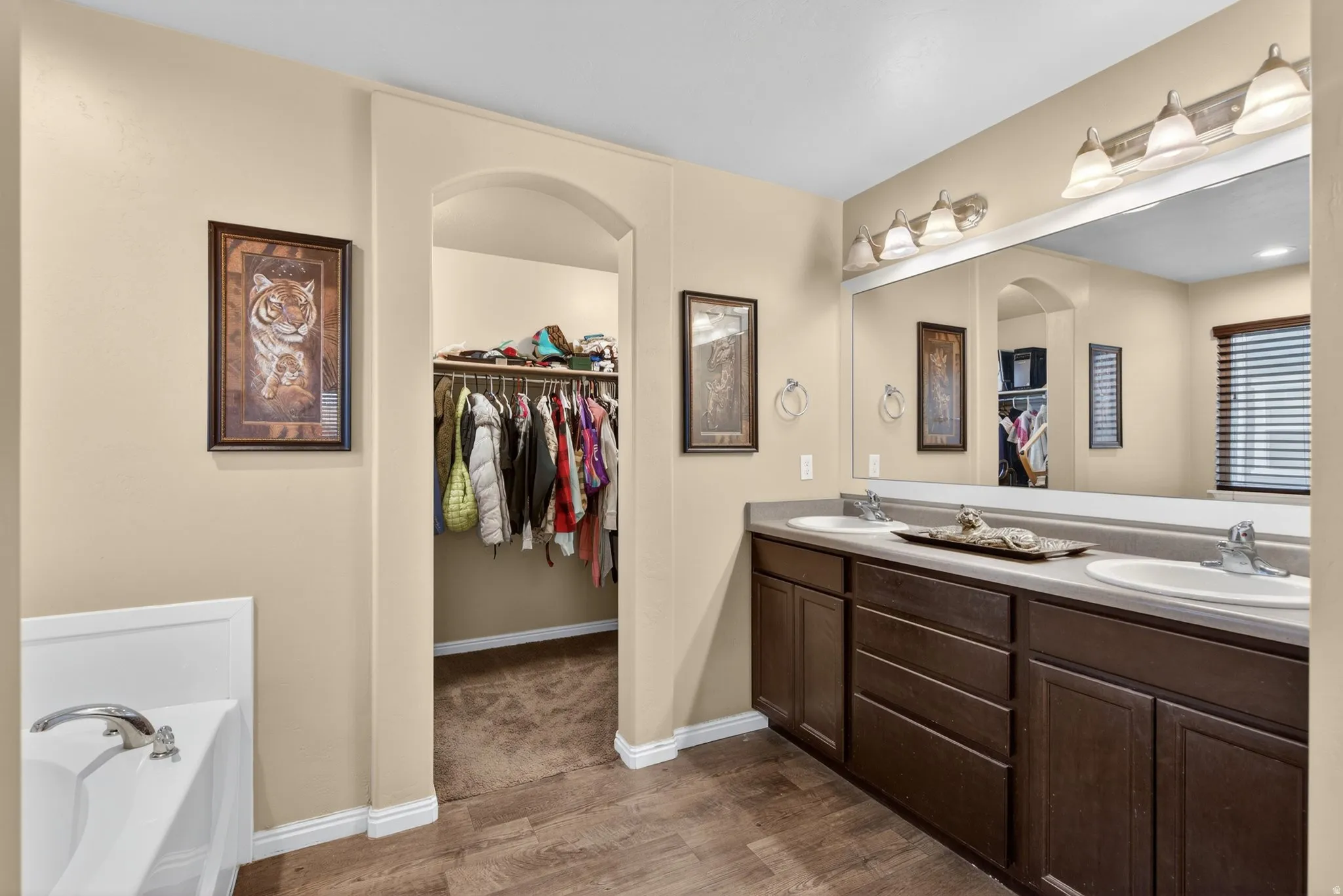 Full bath featuring a spacious closet, dark wood-style floors, double vanity, and a bath