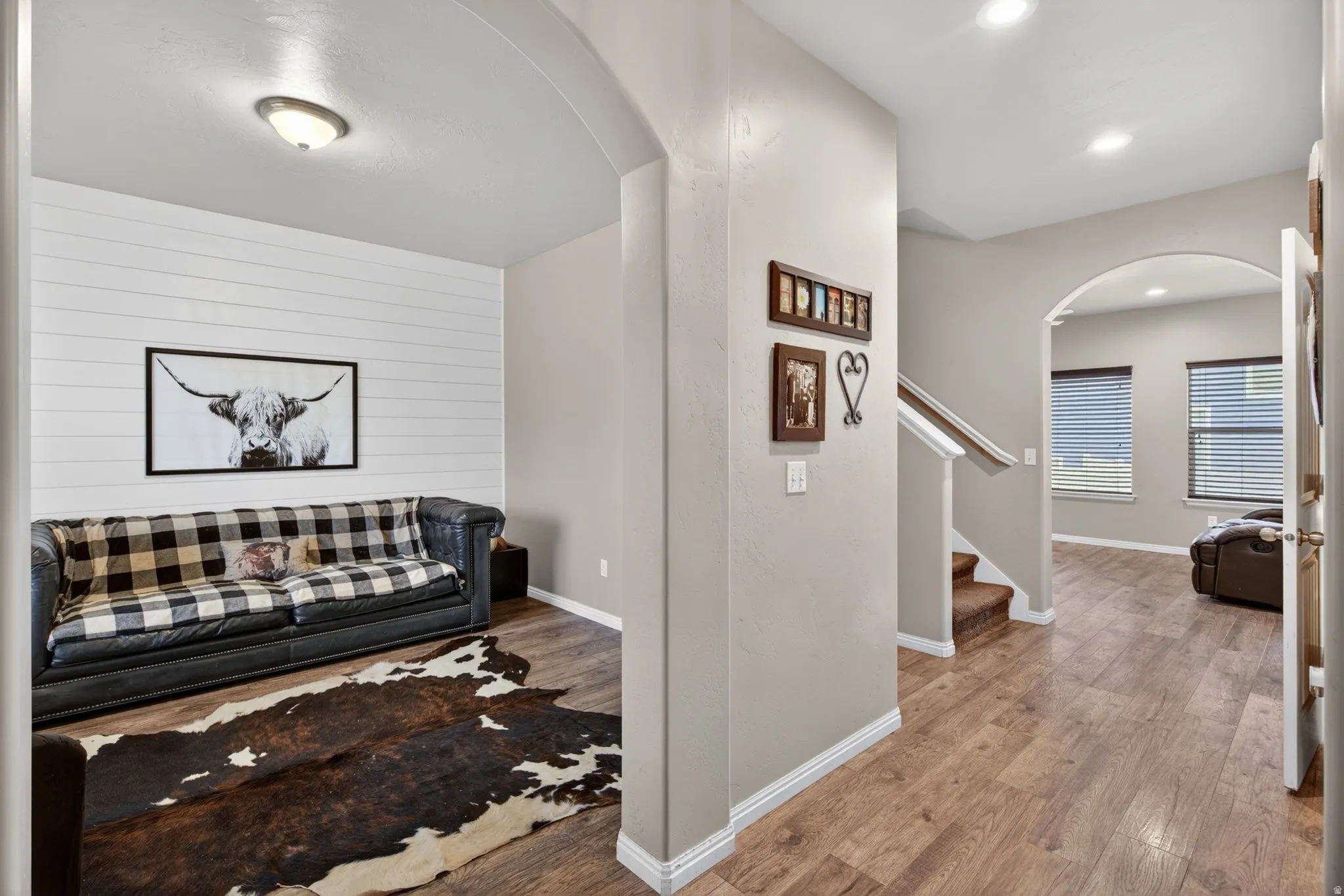 Living room featuring arched walkways, light wood-style floors, and wood walls