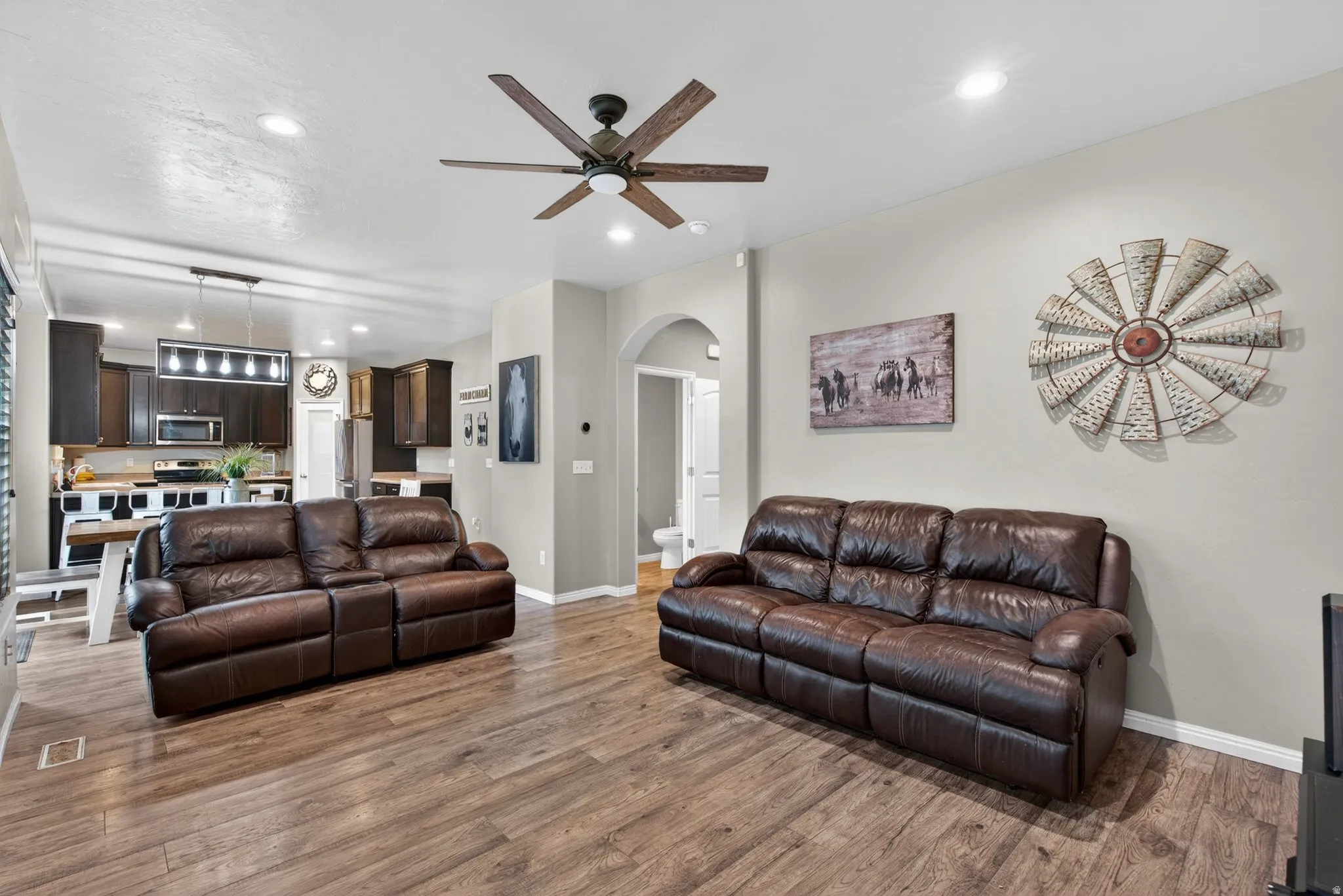 Living room featuring arched walkways, recessed lighting, a ceiling fan, and light wood-style flooring