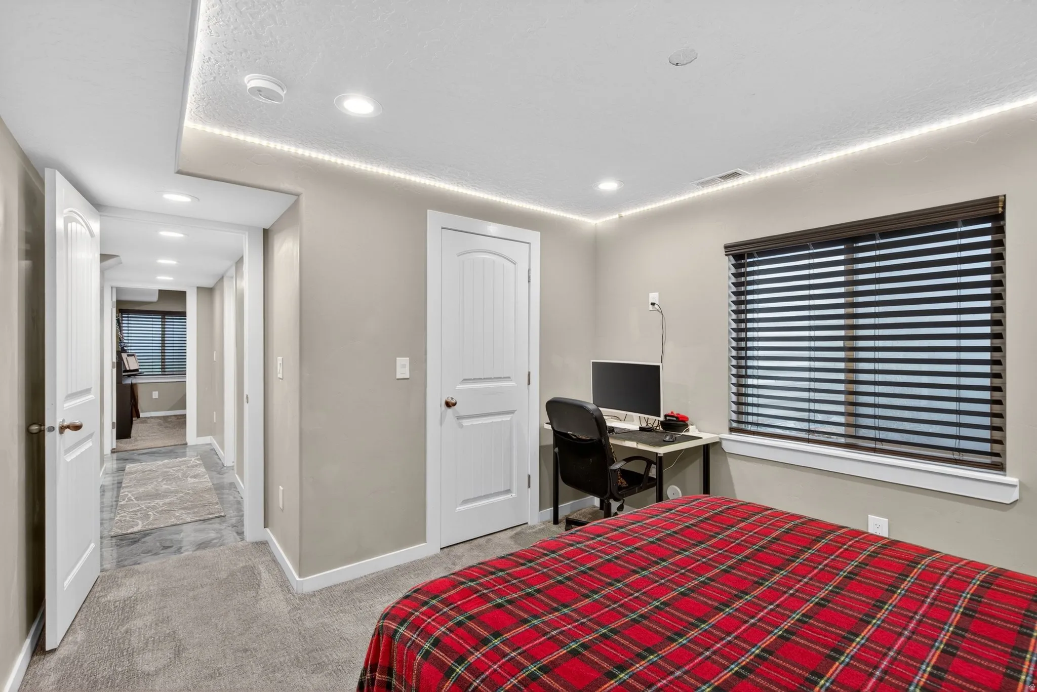 Bedroom with recessed lighting, light carpet, and a desk