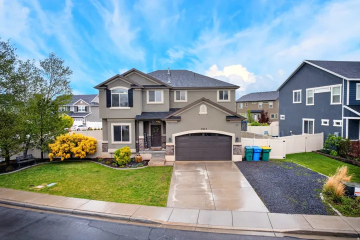 View of front of home featuring driveway, a garage, stone siding, and a residential view