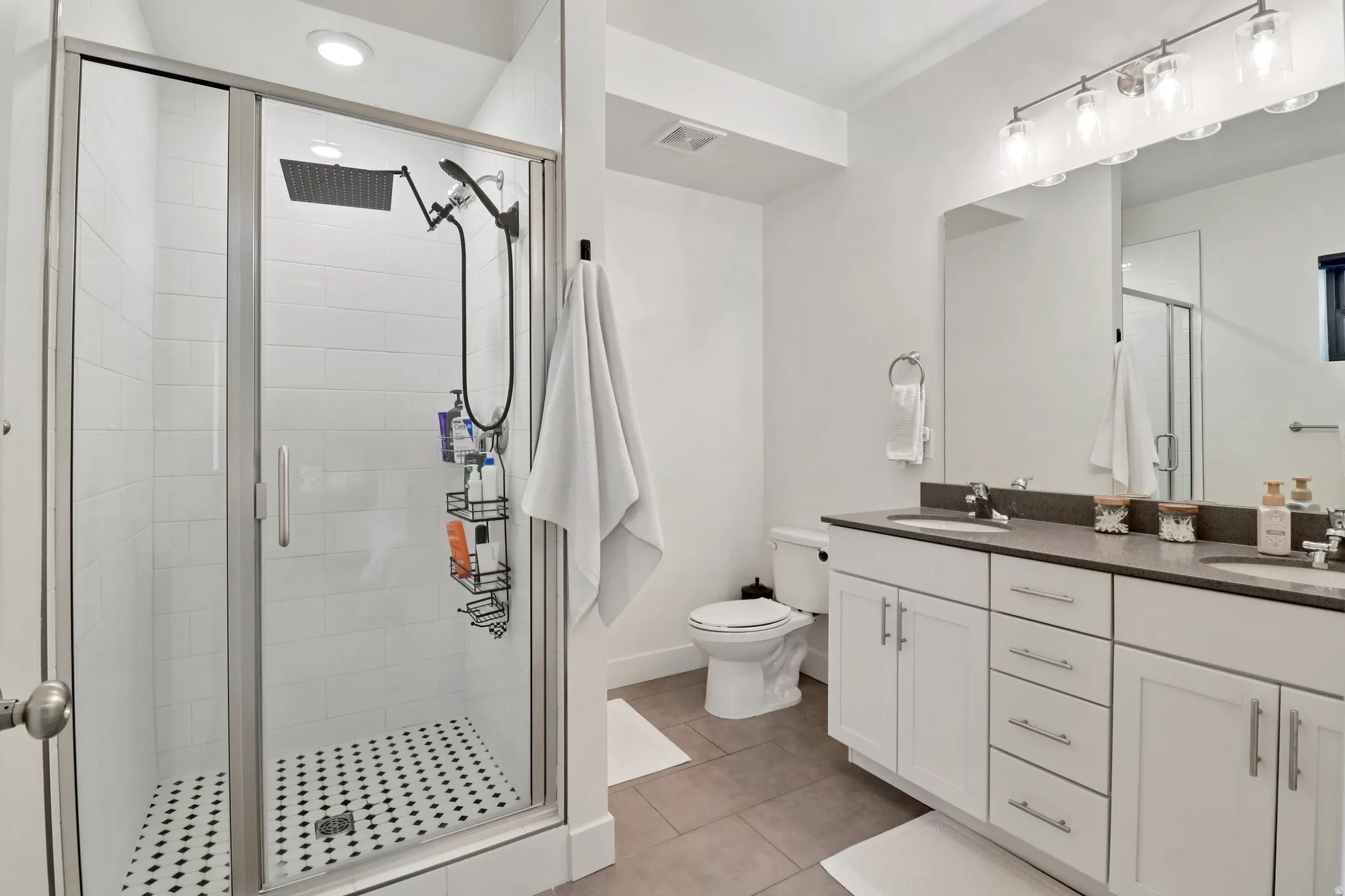 Bathroom with double vanity, a stall shower, and light tile patterned floors