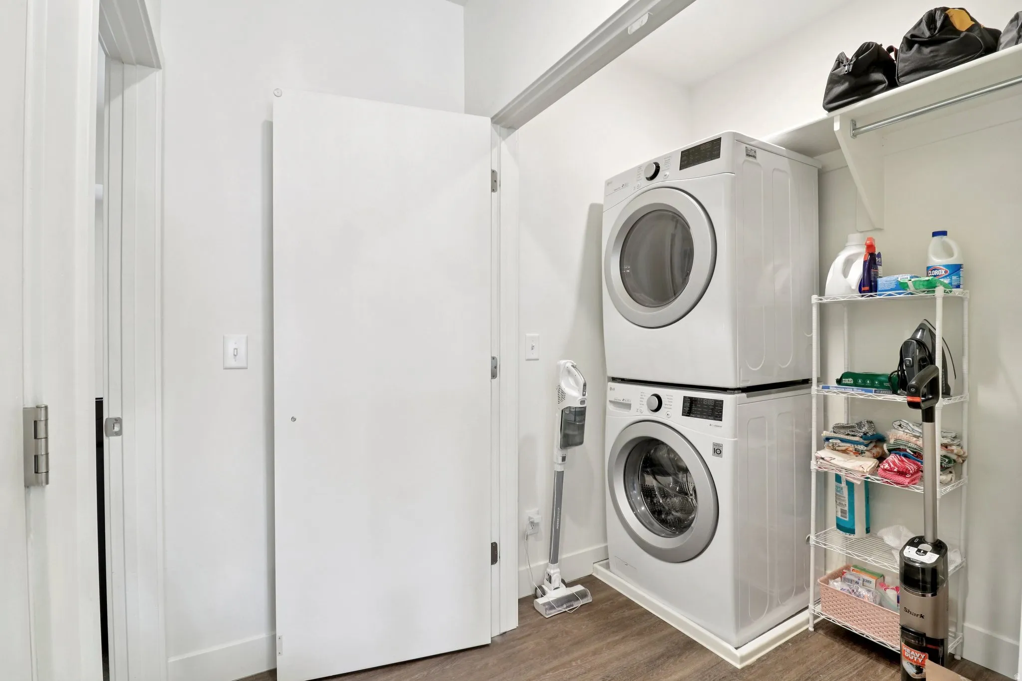 Laundry area featuring dark wood-style floors and stacked washer and clothes dryer