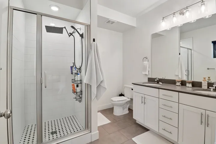 Bathroom with double vanity, a stall shower, and light tile patterned floors