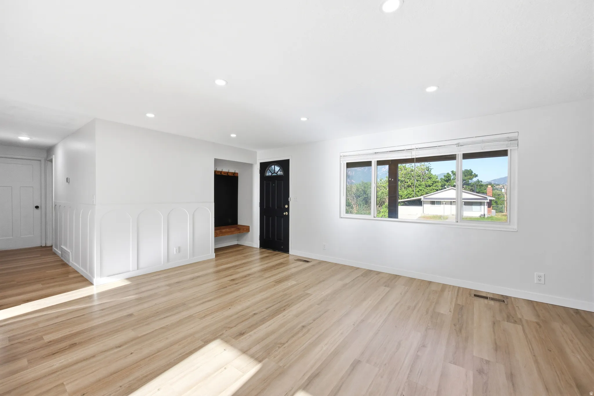 Expansive room featuring light wood-finish flooring, recessed lighting, and a large multi-pane window