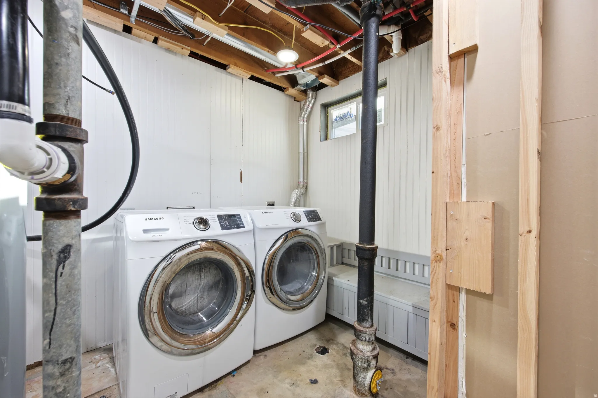 Dedicated laundry area featuring a washer and dryer, exposed ceiling joists, and white beadboard paneling