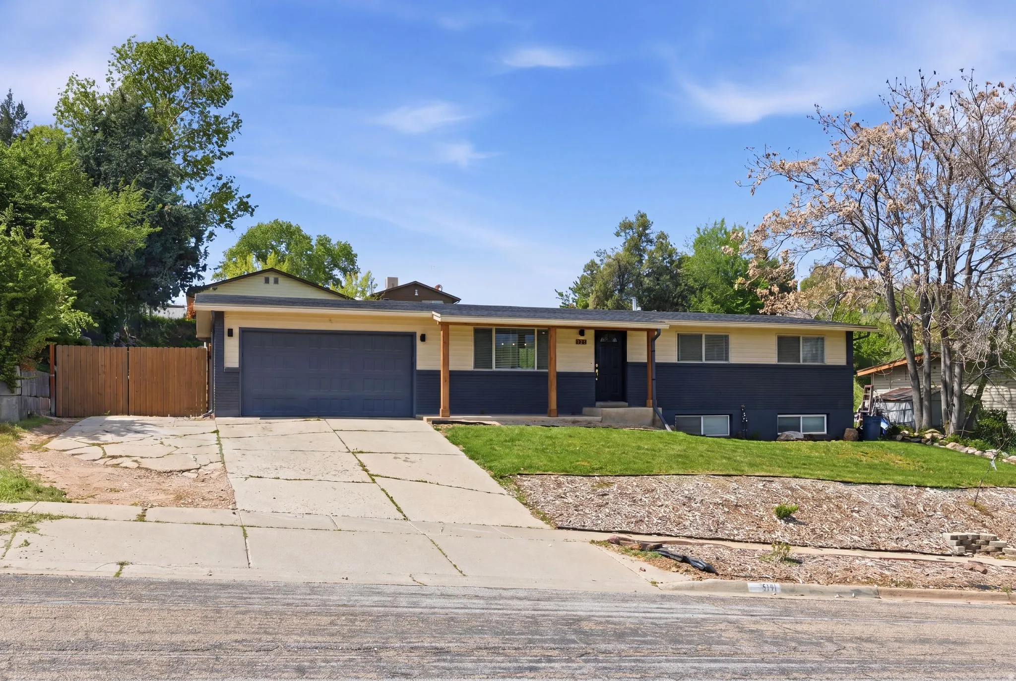 Single story home with concrete driveway, an attached garage, and covered porch